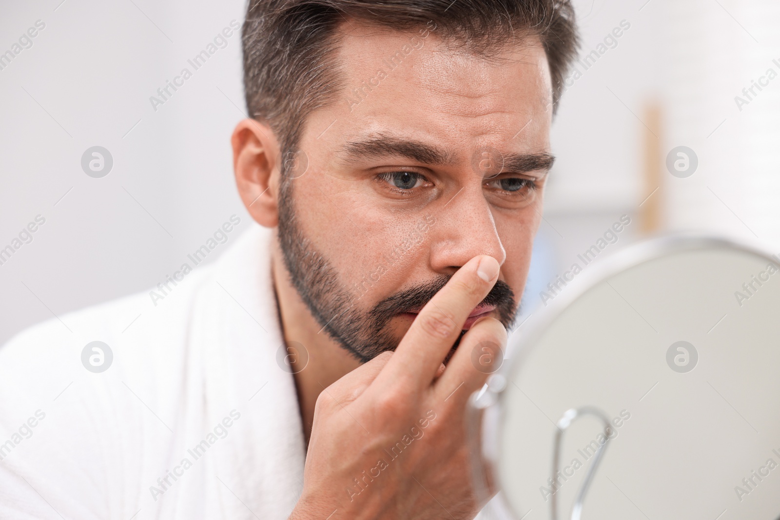 Photo of Man with skin problem looking at mirror indoors