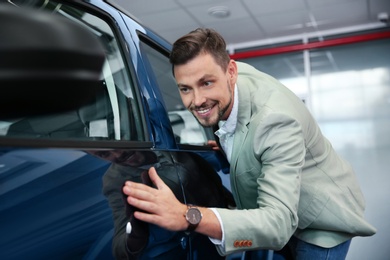 Photo of Man near new car in modern auto dealership