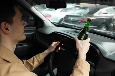 Photo of Man with bottle of beer driving car. Don't drink and drive concept