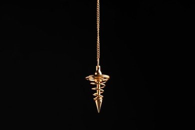 Beautiful golden pendulum with chain on black background. Hypnosis session