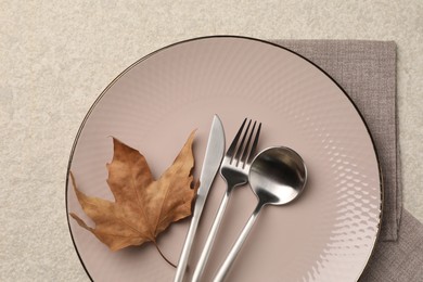 Stylish table setting with cutlery and dry leaf on light surface, top view