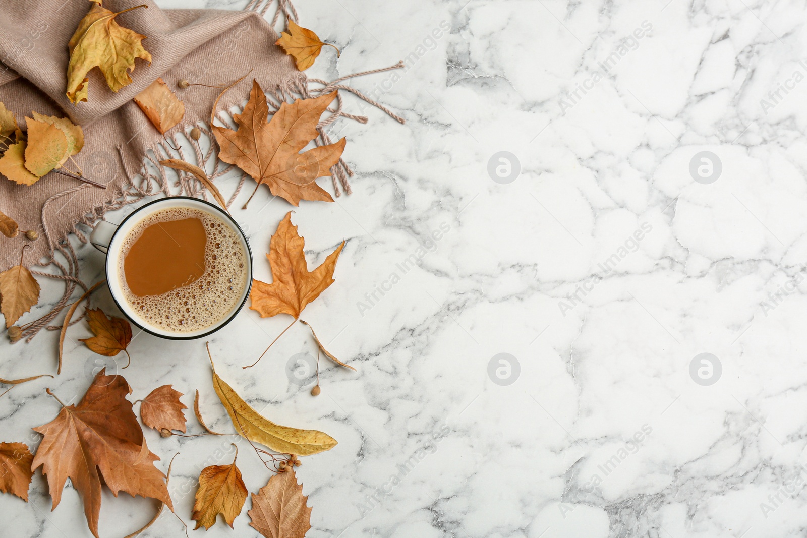 Photo of Flat lay composition with cup of hot drink, scarf and autumn leaves on white marble background, space for text. Cozy atmosphere