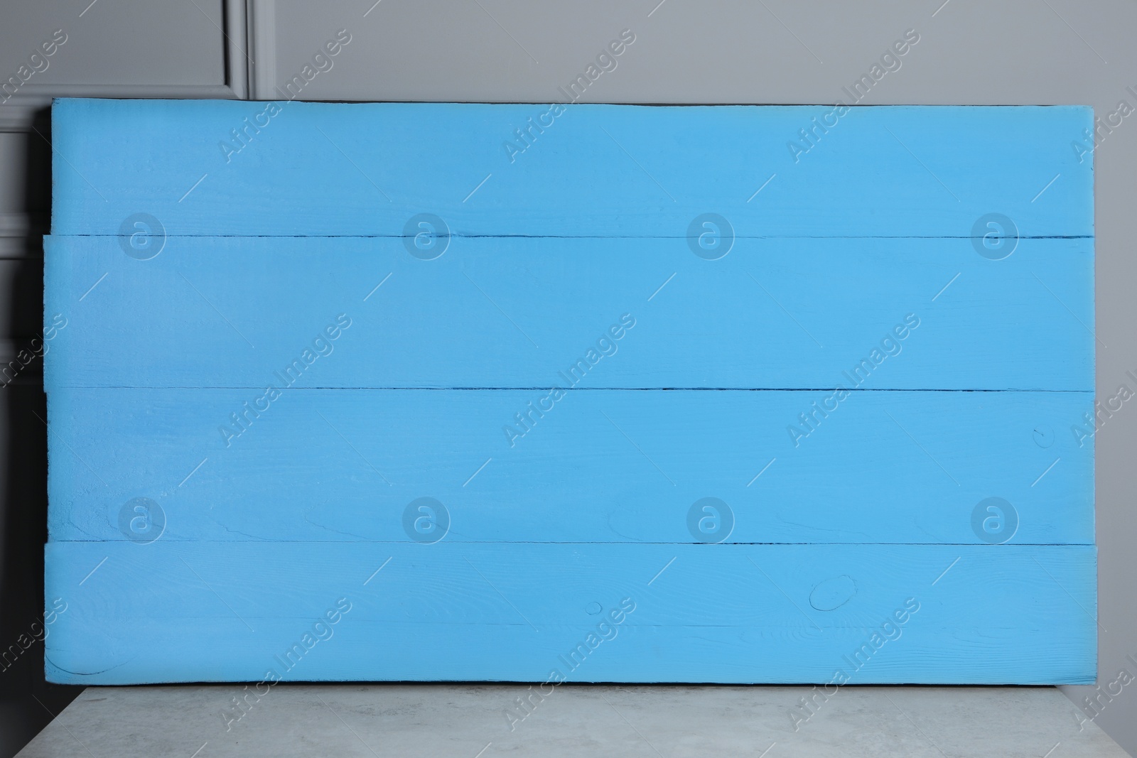 Photo of Texture of light blue wooden board on table near grey wall