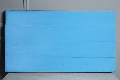 Photo of Texture of light blue wooden board on table near grey wall