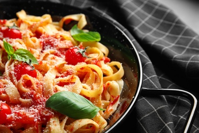 Tasty pasta with basil and tomato sauce on table, closeup