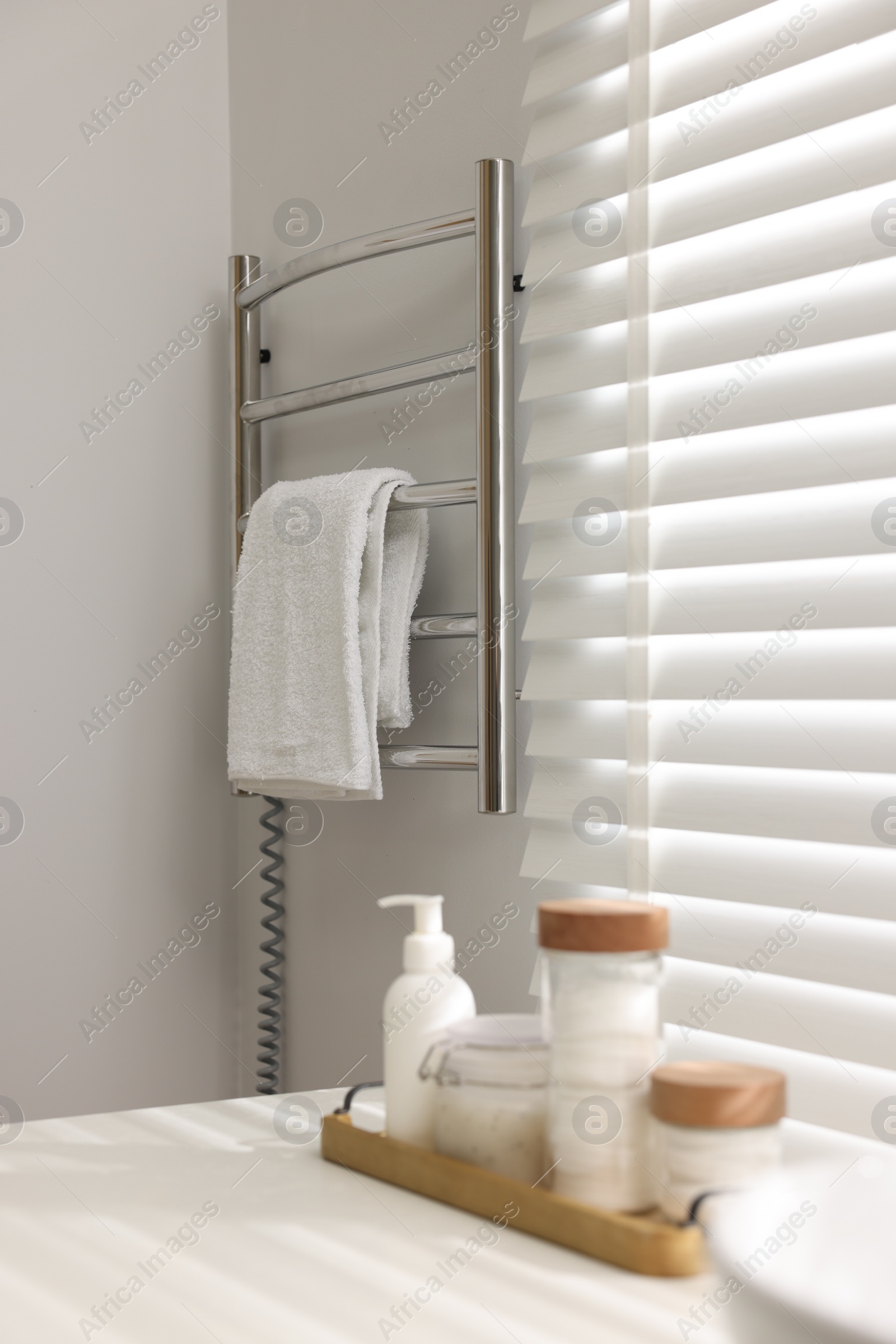 Photo of Heated rail with towel on white wall in bathroom