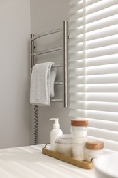 Photo of Heated rail with towel on white wall in bathroom