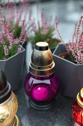 Photo of Grave light with potted heather on granite surface at cemetery