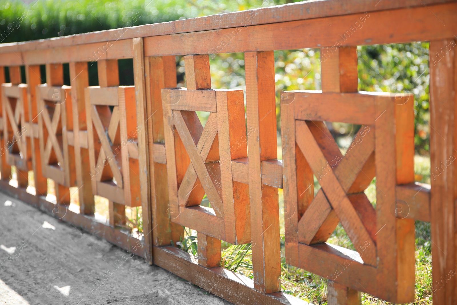 Photo of Beautiful wooden fence near green plants on sunny day outdoors, closeup