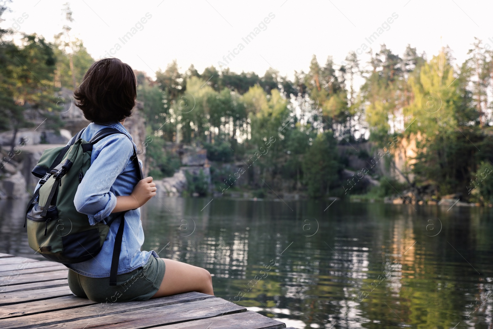 Photo of Young woman on wooden pier near lake. Camping season