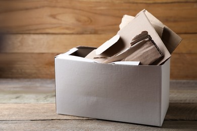 Photo of Box of waste paper on wooden table, space for text