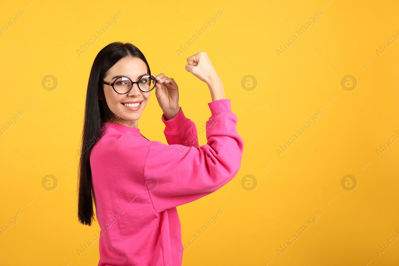 Photo of Strong woman as symbol of girl power on yellow background, space for text. 8 March concept