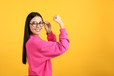 Photo of Strong woman as symbol of girl power on yellow background, space for text. 8 March concept