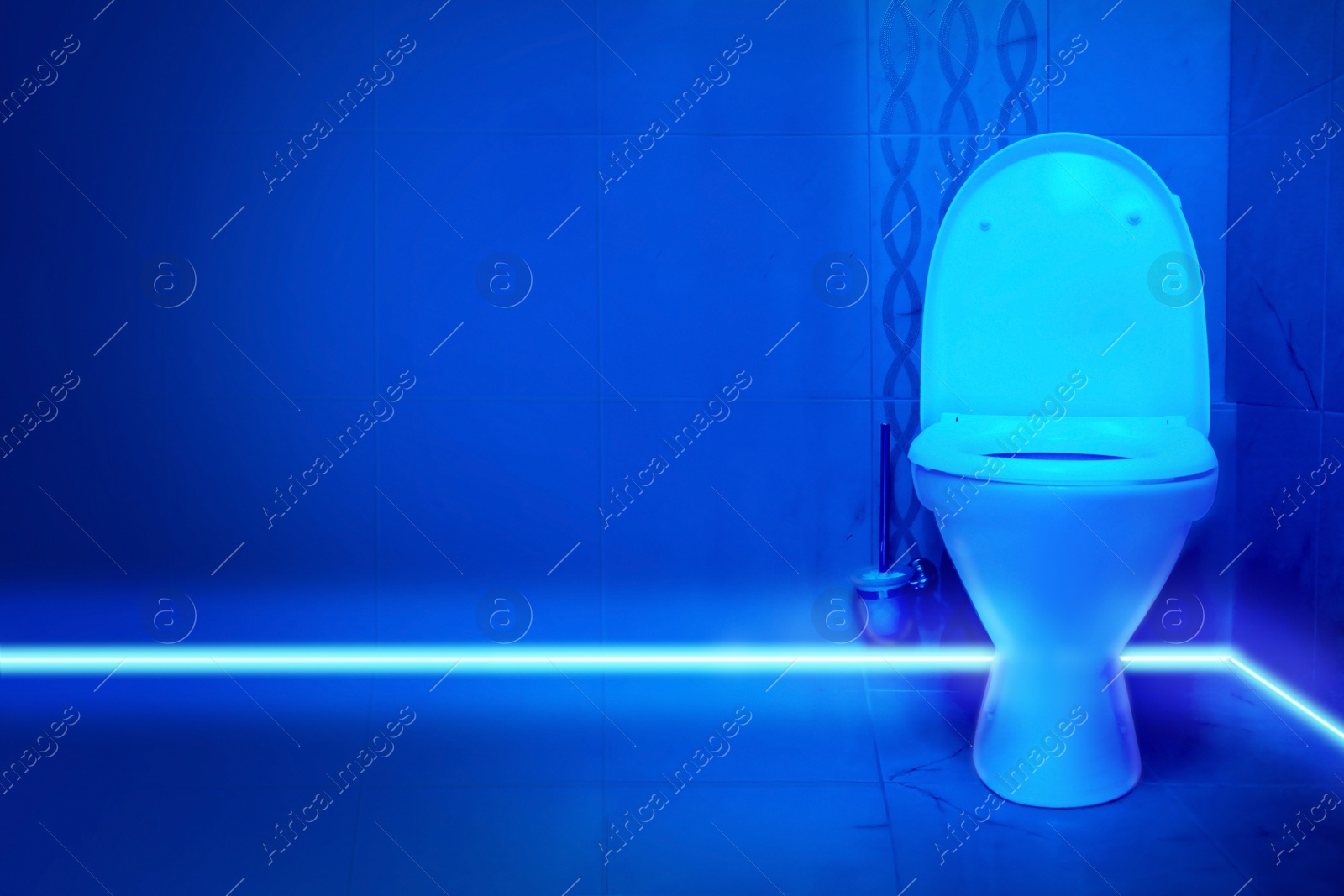 Image of Toilet bowl in public restroom lit with UV blue light