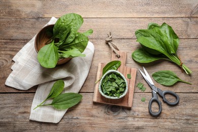 Photo of Broadleaf plantain leaves and scissors on wooden table, flat lay