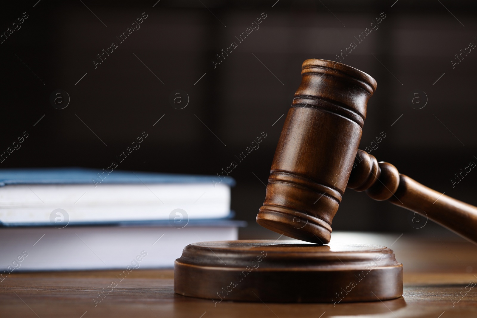 Photo of Wooden gavel and books on table against blurred background, closeup