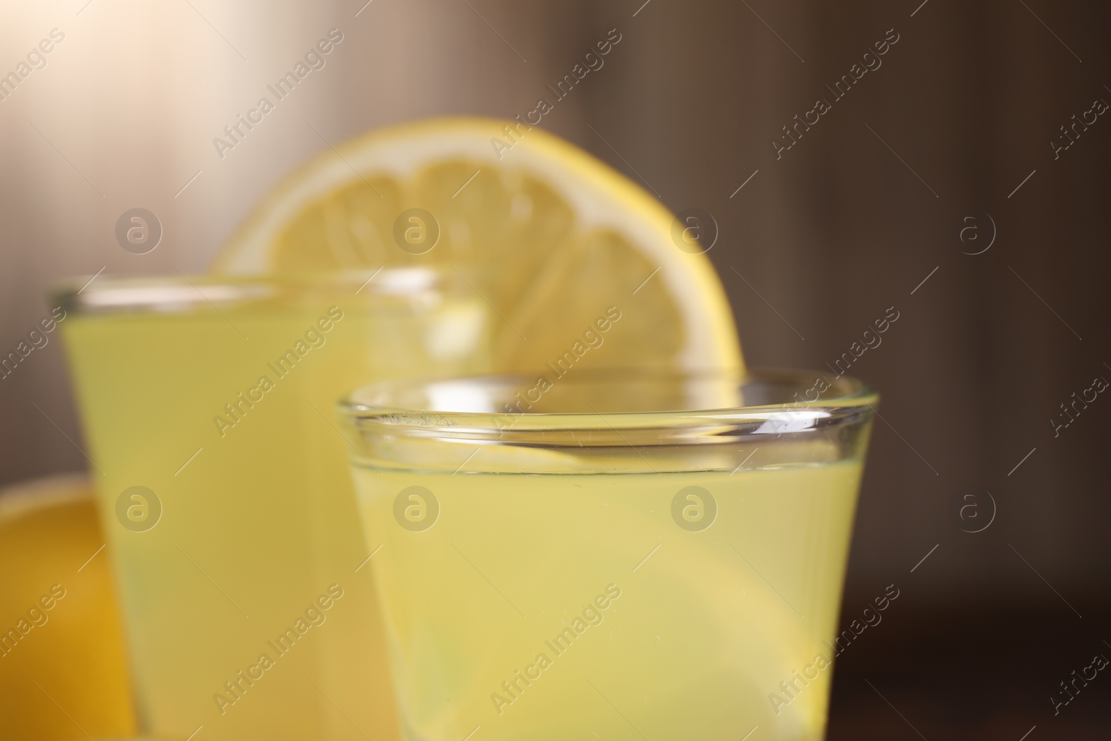 Photo of Shot glasses with tasty limoncello liqueur against blurred background, closeup