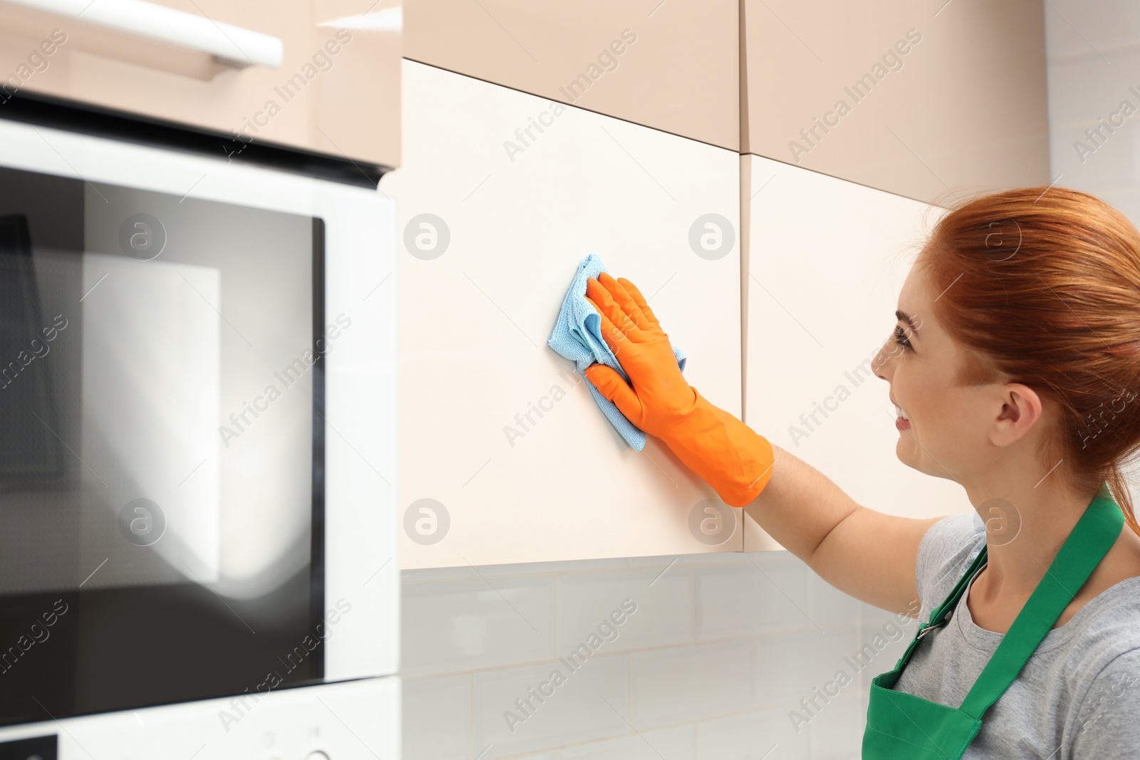 Photo of Woman cleaning kitchen with rag, indoors