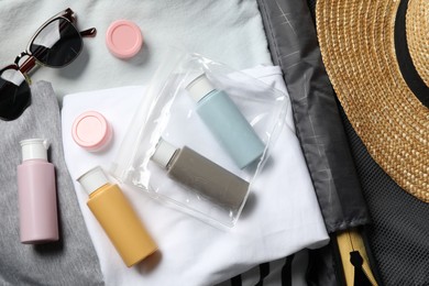 Photo of Cosmetic travel kit, plastic bag and accessories in suitcase, top view