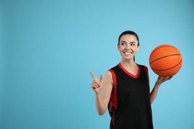 Photo of Basketball player with ball on light blue background. Space for text
