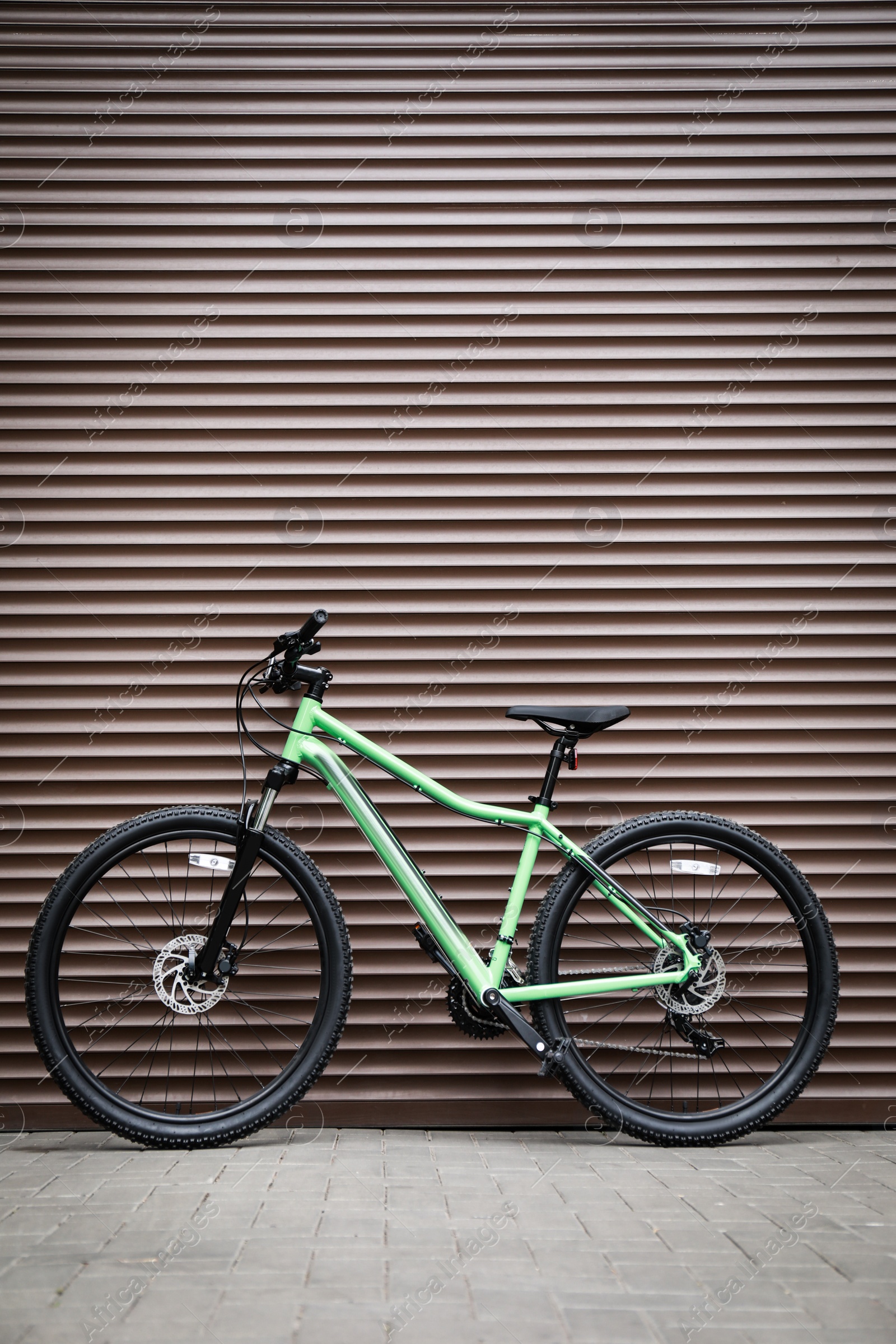 Photo of New modern color bicycle near brown wall outdoors