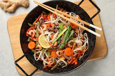 Shrimp stir fry with noodles and vegetables in wok on grey table, top view
