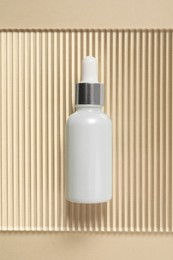 Bottle of cosmetic serum on beige background, top view