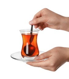 Photo of Woman stirring Turkish tea in glass on white background, closeup