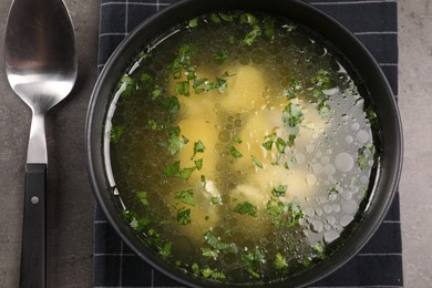 Photo of Delicious chicken soup with parsley and spoon on grey table, flat lay