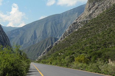 Photo of Picturesque view of big mountains and bushes near road under cloudy sky