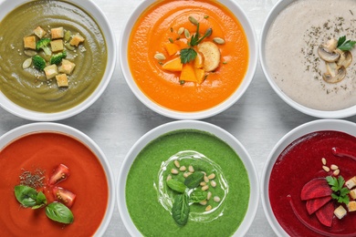 Various soups in bowls on wooden background, top view. Healthy food