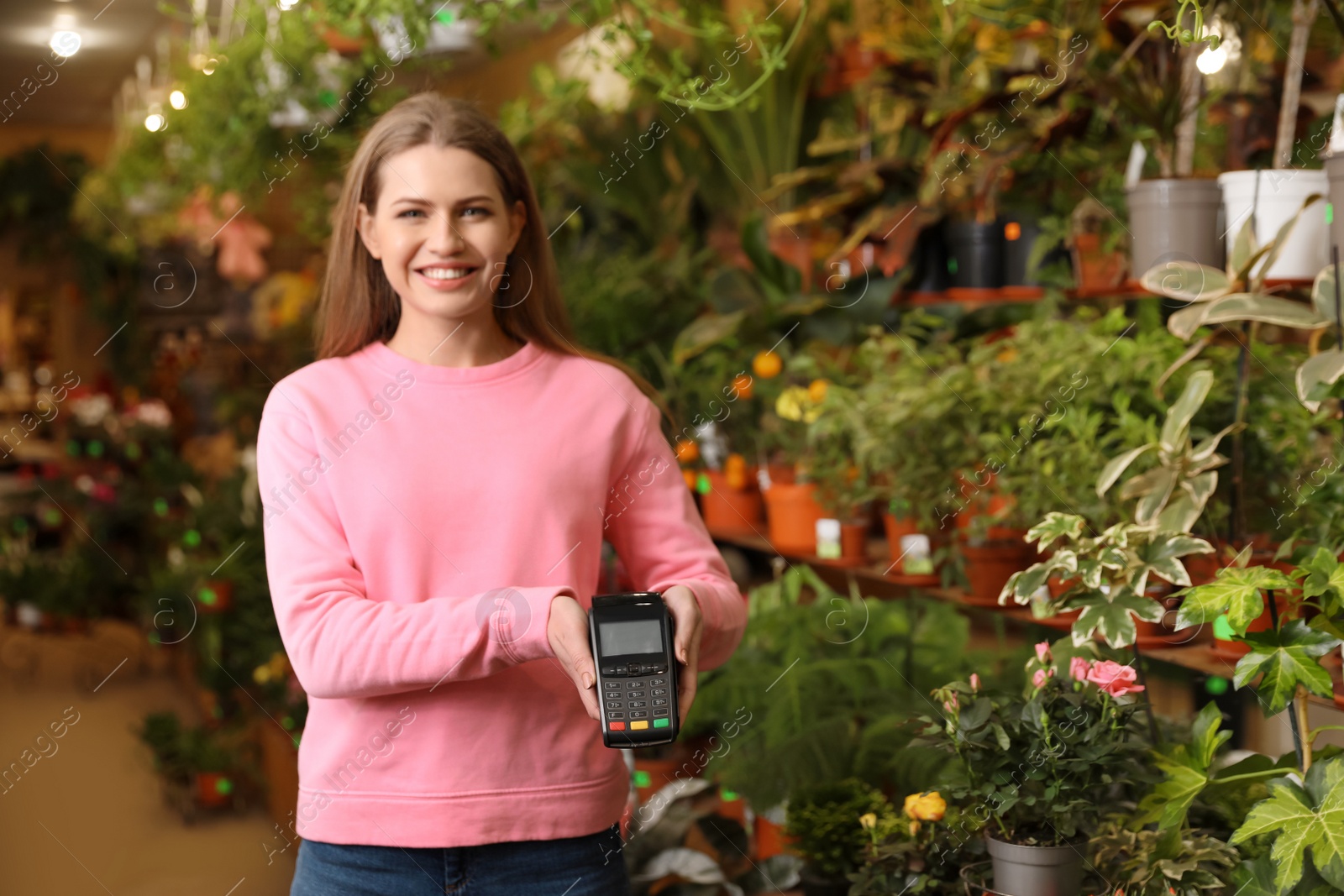 Photo of Woman holding payment terminal in floral shop. Space for text