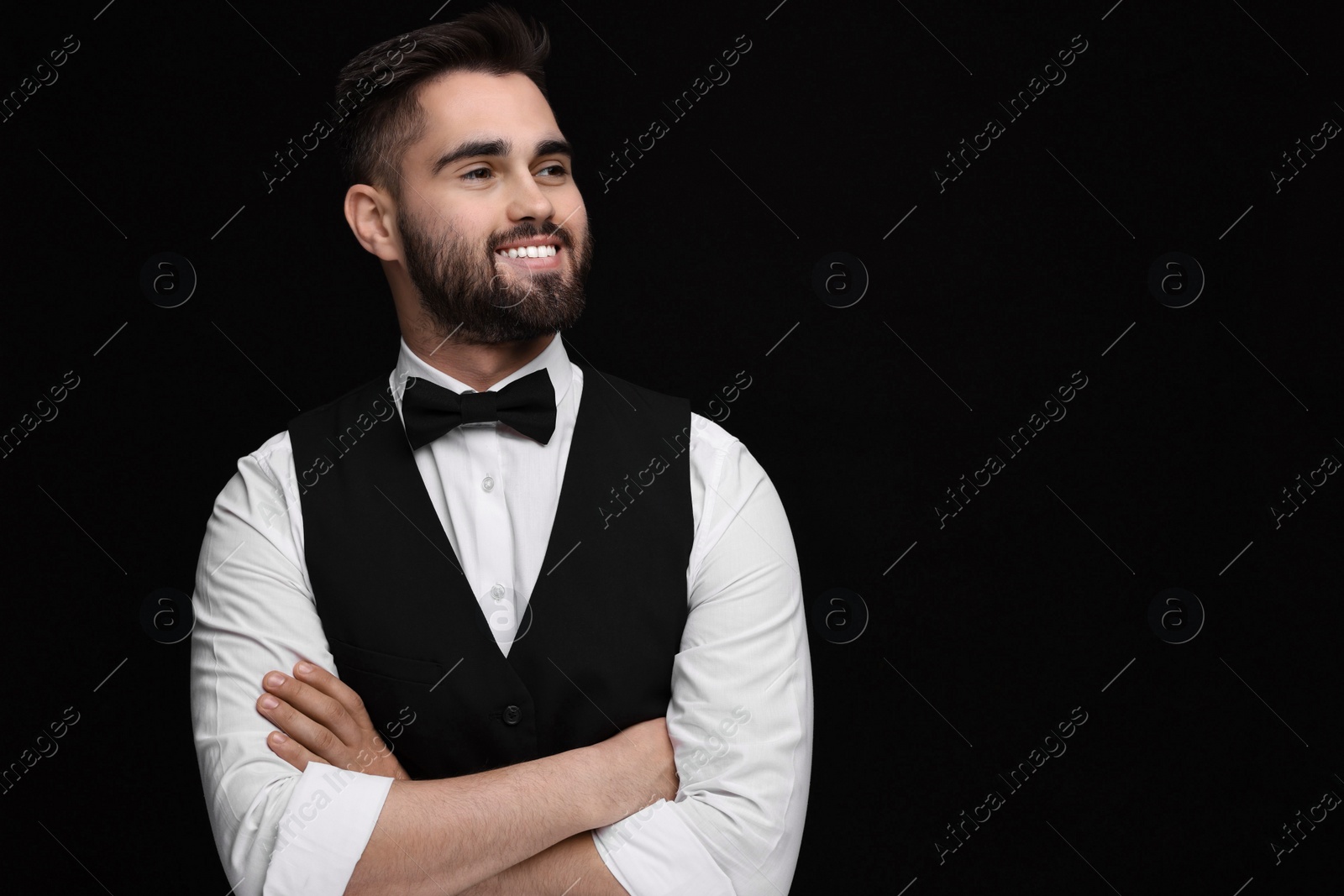 Photo of Portrait of smiling man in shirt and bow tie on black background. Space for text