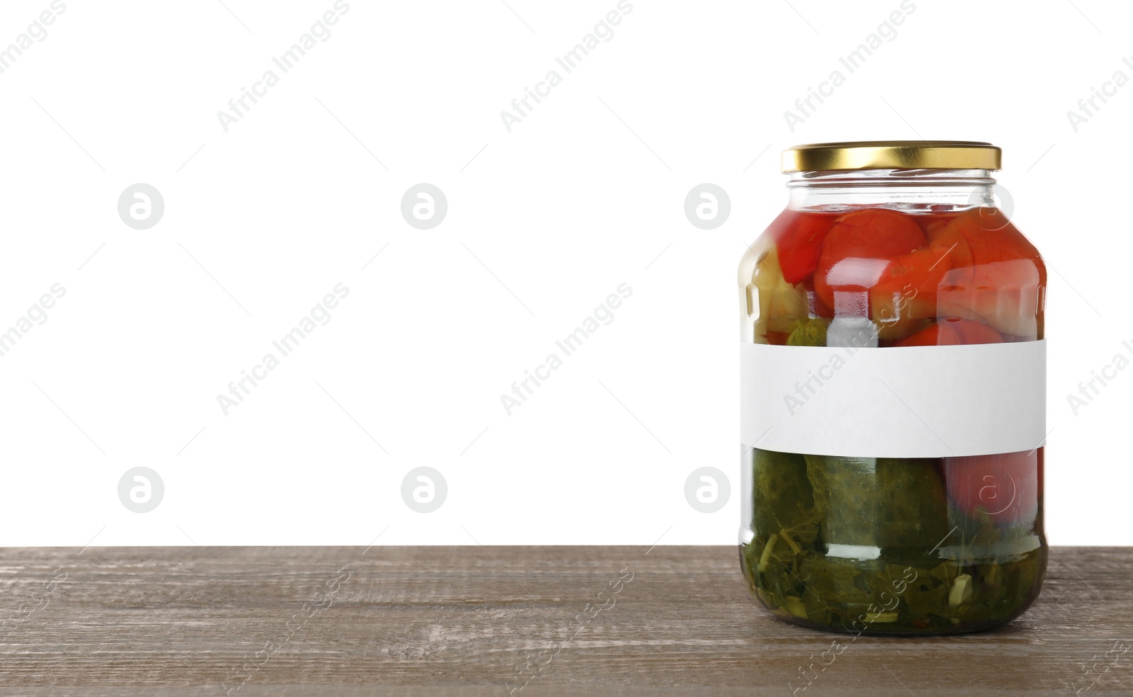 Photo of Jar of pickled vegetables with blank label on wooden table against white background. Space for text