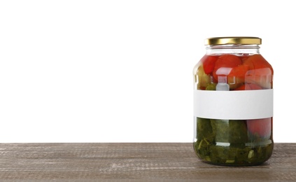 Jar of pickled vegetables with blank label on wooden table against white background. Space for text