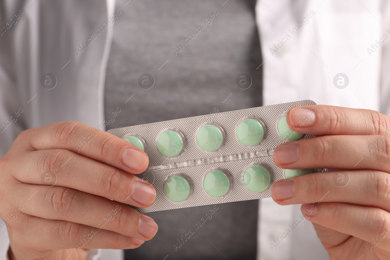 Photo of Woman holding blister of green pills, closeup