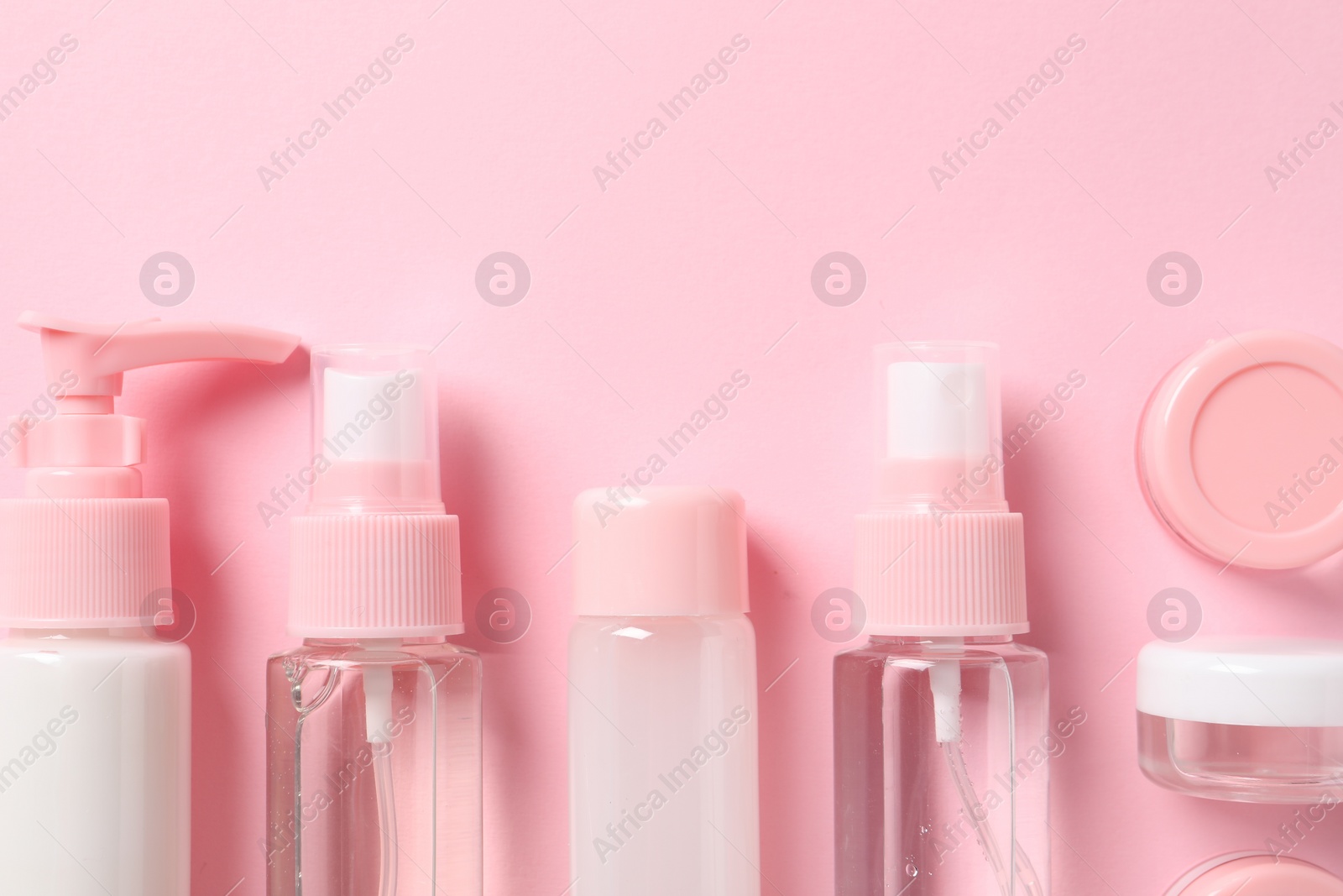 Photo of Cosmetic travel kit on pink background, flat lay. Space for text