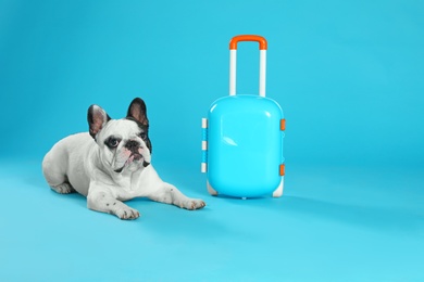 Photo of French bulldog with little suitcase on blue background. Space for text
