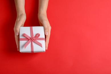 Photo of Woman holding gift box on color background, top view