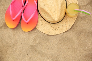 Straw hat, flip flops and refreshing drink on sand, flat lay with space for text. Beach accessories