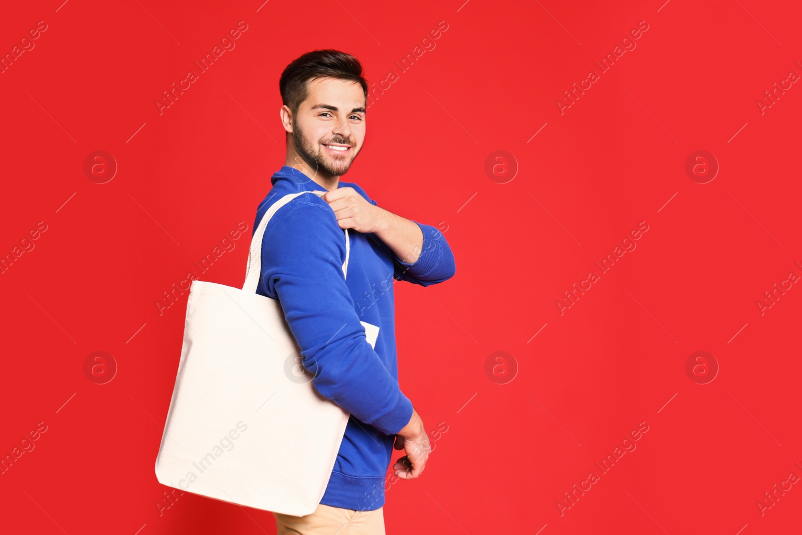 Photo of Portrait of young man with eco bag on red background. Space for text