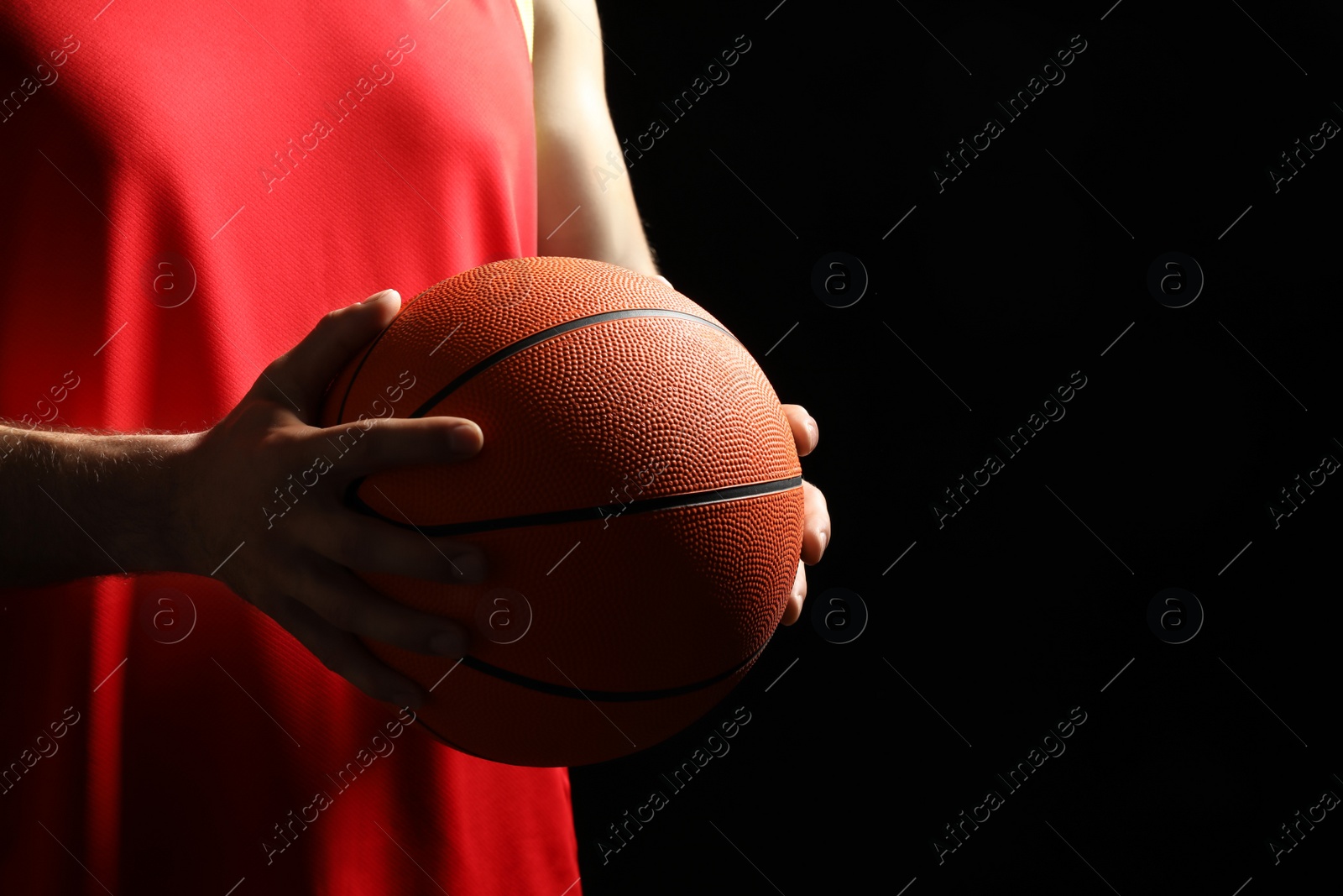 Photo of Basketball player with ball on black background, closeup. Space for text