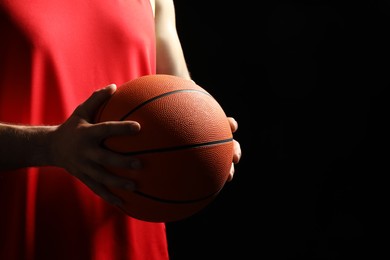 Basketball player with ball on black background, closeup. Space for text