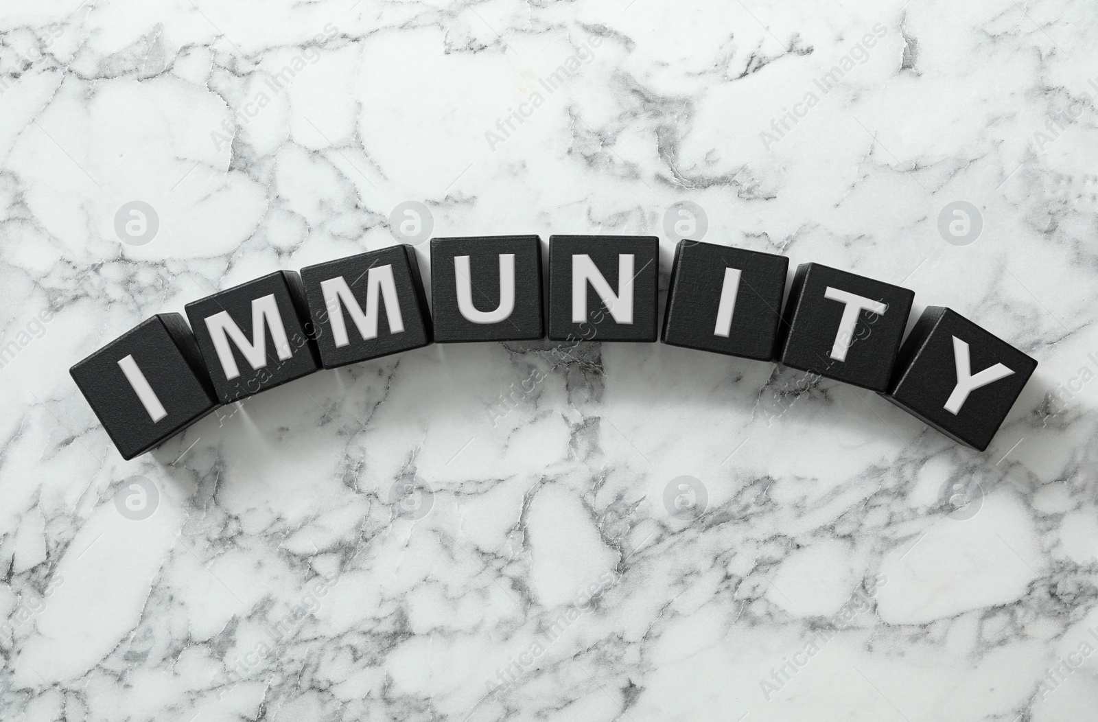 Photo of Black cubes with word Immunity on white marble table, flat lay