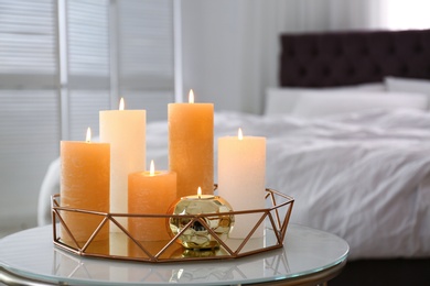 Golden tray with burning candles on table in bedroom