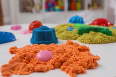 Bright kinetic sand and toys on white table indoors