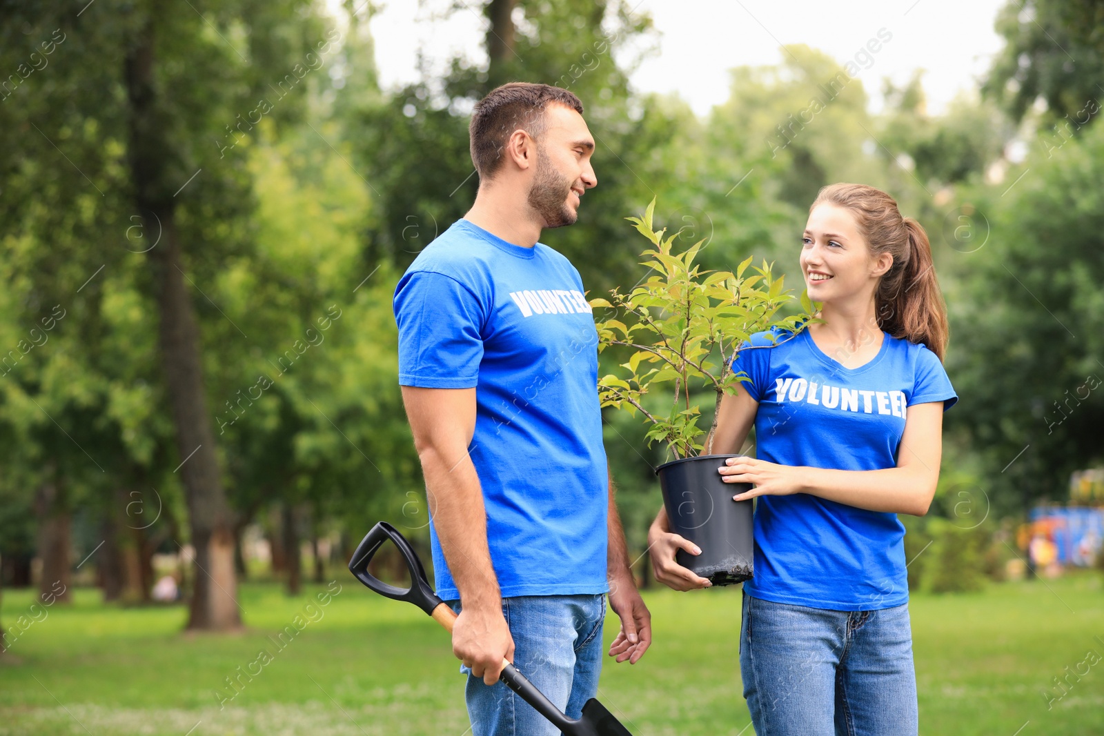 Photo of Young volunteers with tree seedling in green park. Charity work