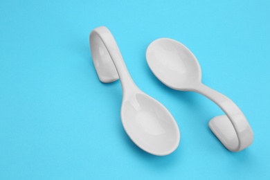 Photo of Clean empty ceramic appetizer spoons on blue background, space for text