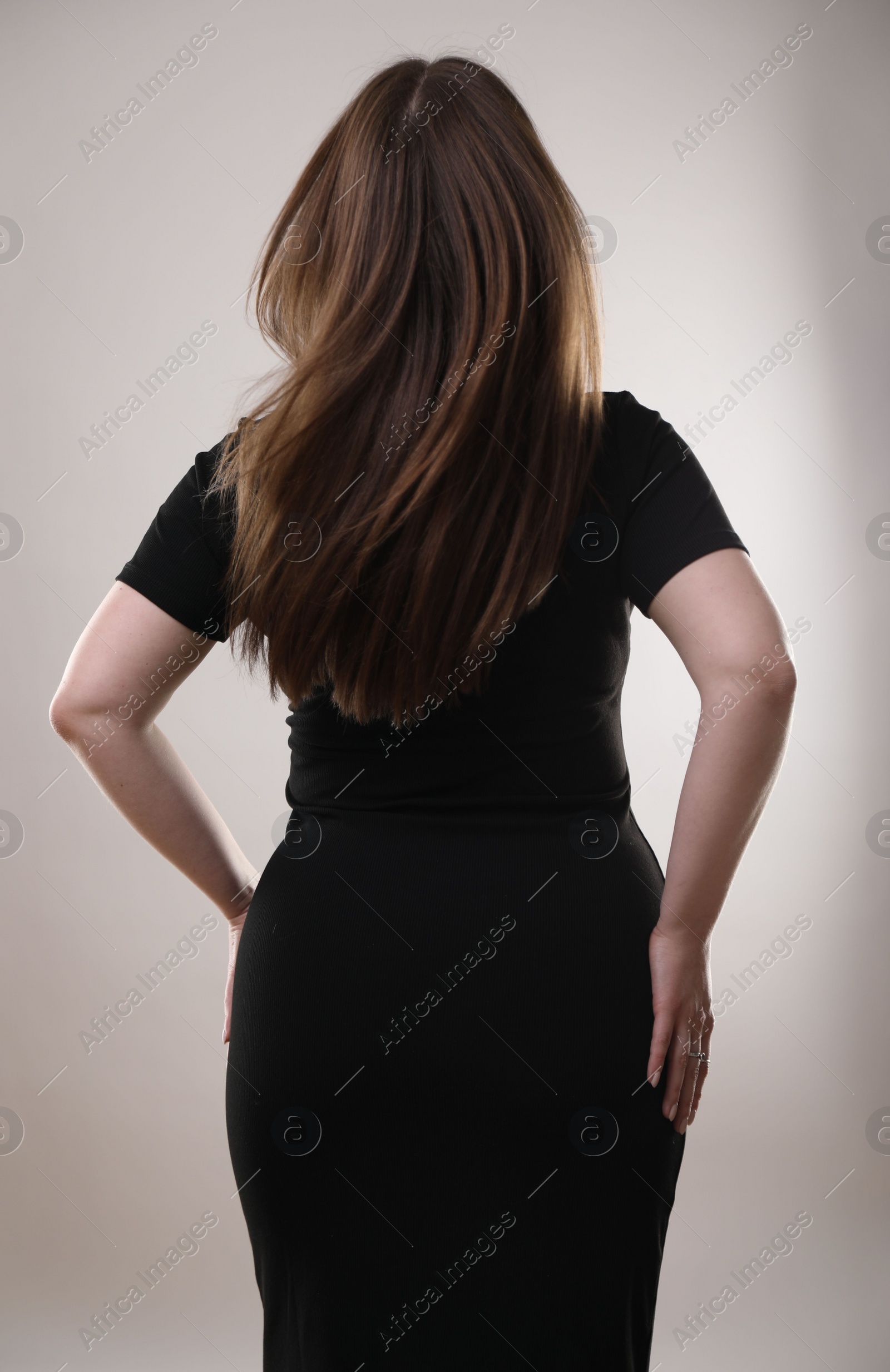 Photo of Woman posing on gray background, back view