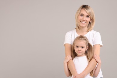 Photo of Family portrait of happy mother and daughter on grey background. Space for text